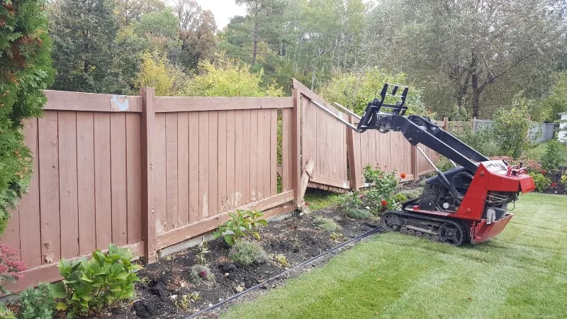 Compact track machine pulling fence posts and panels during removal